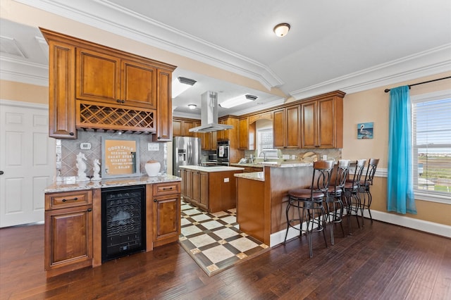 kitchen featuring beverage cooler, stainless steel appliances, island exhaust hood, brown cabinetry, and dark wood finished floors