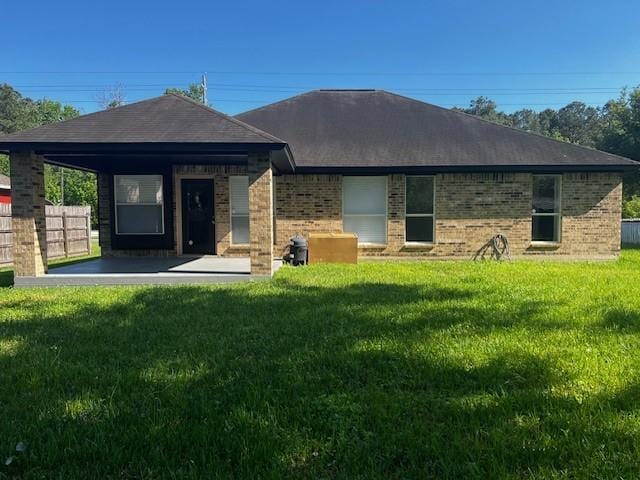 4027 N Fm 565th Rd, Mont Belvieu, TX 77523 - rear view of house with a lawn, a patio area, brick siding, and roof with shingles