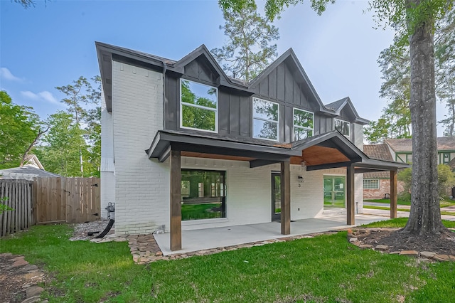 rear view of house featuring a patio area, brick siding, a yard, and fence