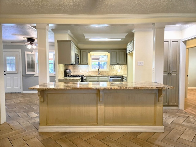kitchen featuring stainless steel appliances, a textured ceiling, ornate columns, and a kitchen bar
