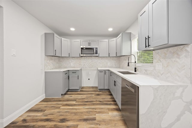 3806 Zephyr St, Houston, TX 77021 - kitchen featuring a sink, appliances with stainless steel finishes, gray cabinetry, wood finished floors, and decorative backsplash