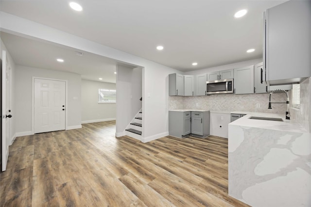 3806 Zephyr St, Houston, TX 77021 - kitchen featuring stainless steel microwave, light stone counters, gray cabinets, light wood-style floors, and a sink