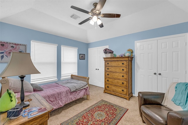 bedroom with light colored carpet, multiple closets, lofted ceiling, and a ceiling fan