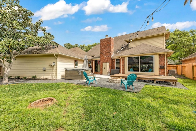 rear view of house with a hot tub, a patio area, and brick siding