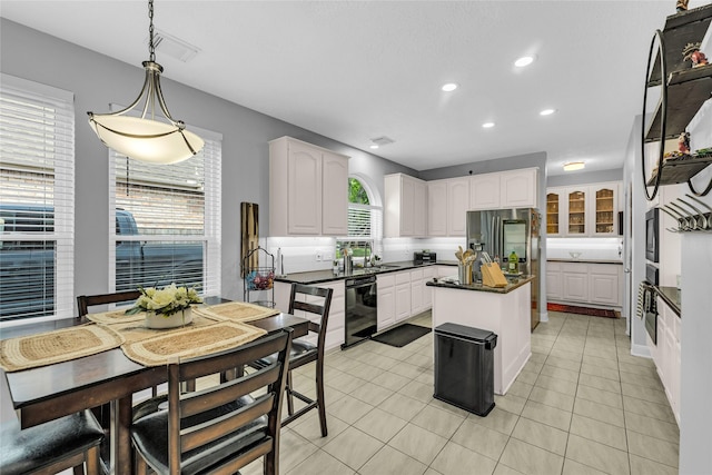 kitchen featuring dishwasher, dark countertops, fridge with ice dispenser, white cabinets, and a kitchen island