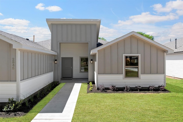 view of front of house featuring board and batten siding, a front lawn, and roof with shingles