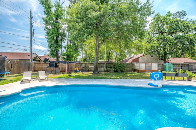view of swimming pool featuring a fenced in pool, a fenced backyard, a trampoline, and a lawn