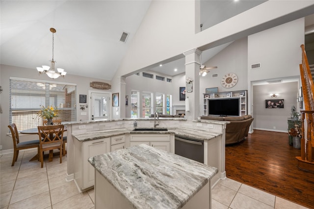 kitchen featuring a sink, open floor plan, light tile patterned floors, stainless steel dishwasher, and a spacious island