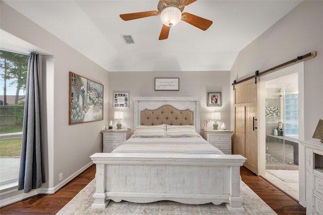 bedroom featuring a barn door, dark wood finished floors, a ceiling fan, lofted ceiling, and visible vents