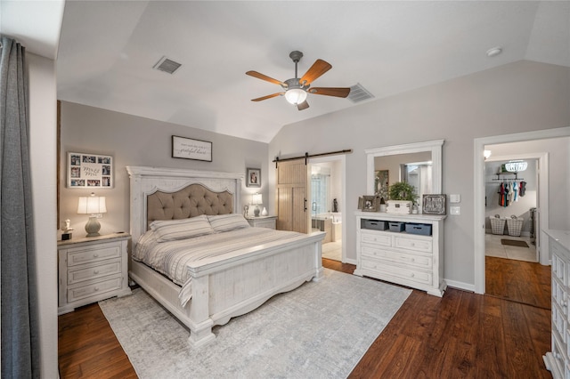 bedroom with visible vents, a barn door, wood finished floors, and lofted ceiling