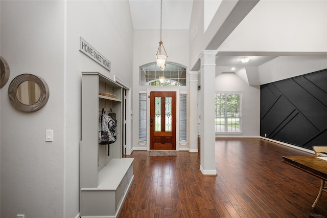foyer featuring baseboards, decorative columns, dark wood finished floors, and high vaulted ceiling