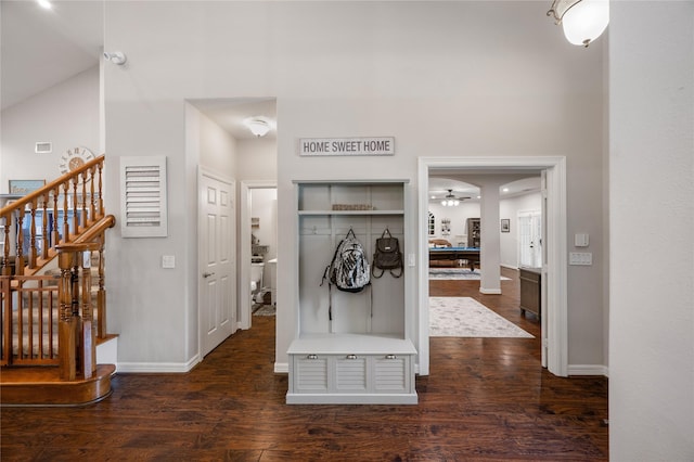 mudroom featuring baseboards, a towering ceiling, and dark wood-style floors