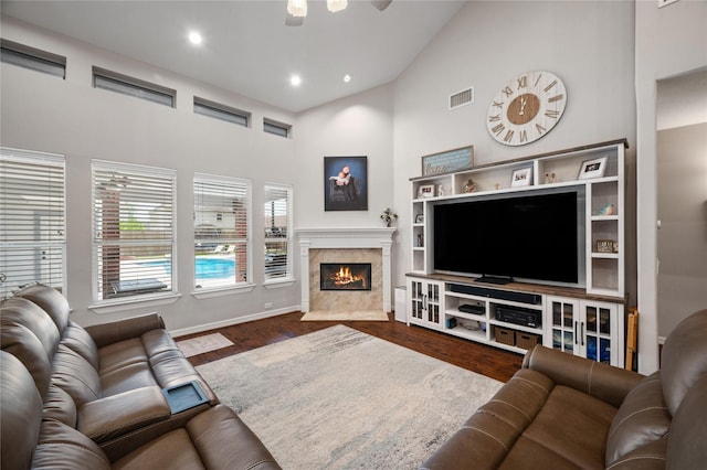 living room featuring high vaulted ceiling, dark wood finished floors, a ceiling fan, a high end fireplace, and visible vents