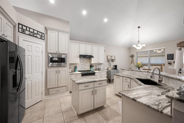 kitchen featuring a sink, tasteful backsplash, under cabinet range hood, a center island with sink, and black appliances