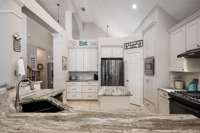 kitchen with backsplash, appliances with stainless steel finishes, a sink, light stone counters, and under cabinet range hood