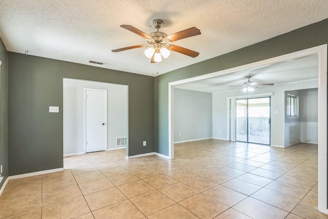 spare room with light tile patterned flooring, a textured ceiling, ceiling fan, and visible vents