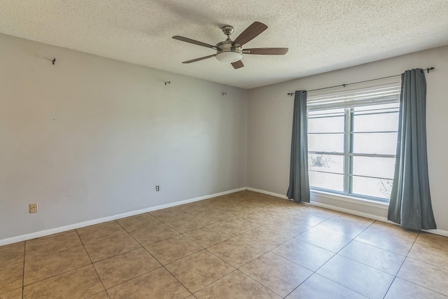tiled spare room with baseboards, a textured ceiling, and ceiling fan