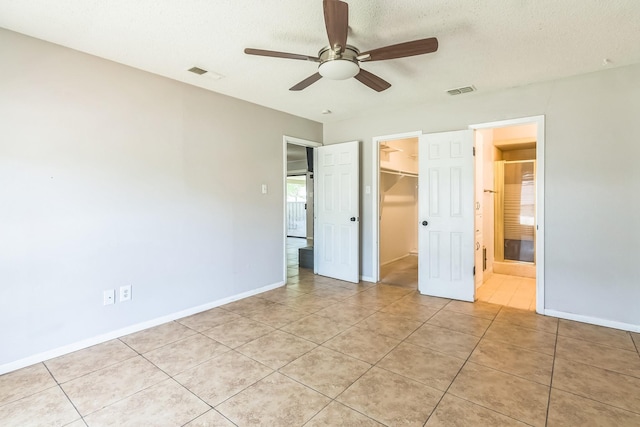 unfurnished bedroom with visible vents, a spacious closet, a closet, and light tile patterned flooring