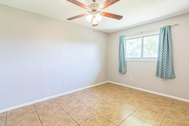 unfurnished room with a textured ceiling, light tile patterned flooring, baseboards, and a ceiling fan