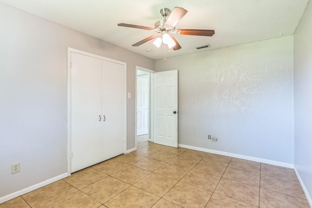 unfurnished bedroom featuring a closet, light tile patterned floors, baseboards, and visible vents