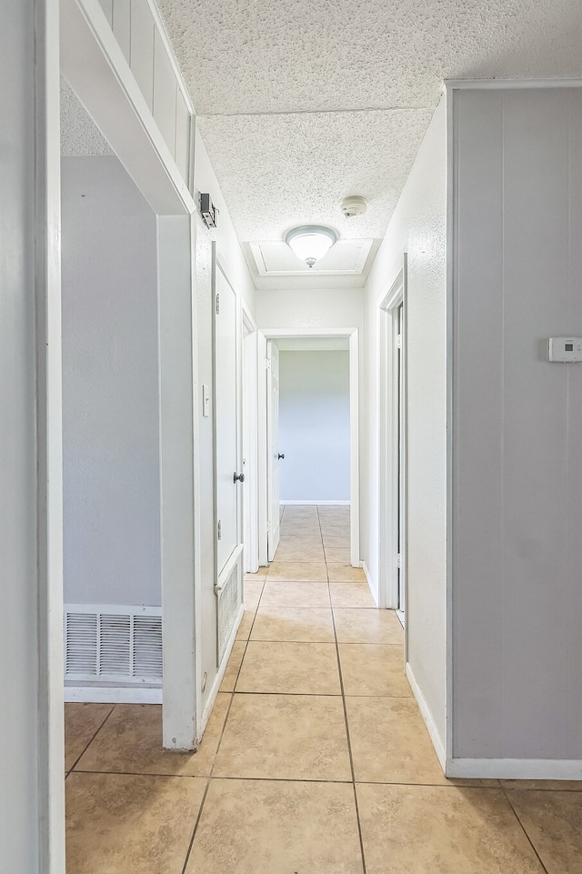 hallway featuring light tile patterned floors, visible vents, and baseboards