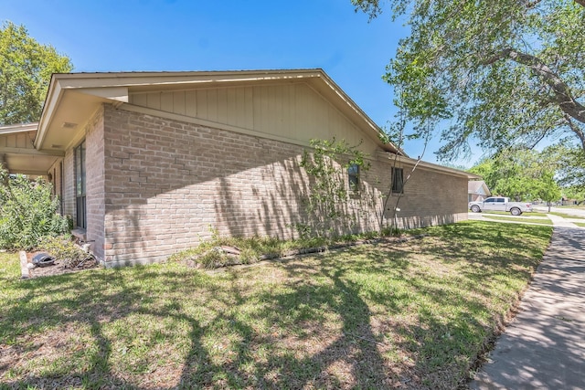 view of property exterior featuring brick siding and a lawn