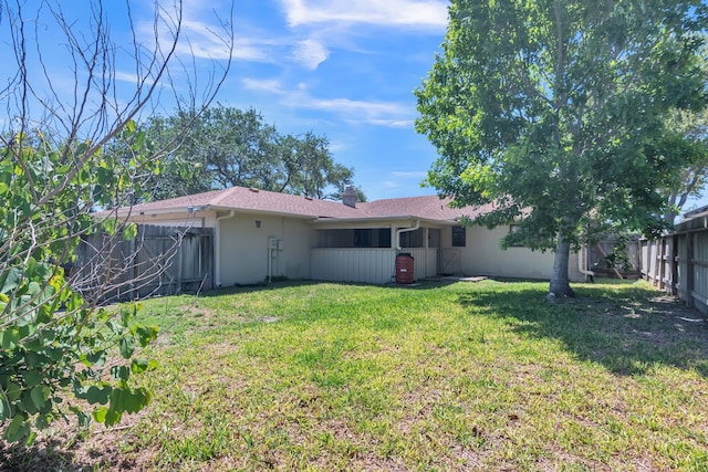back of house with a yard, a fenced backyard, stucco siding, and a chimney