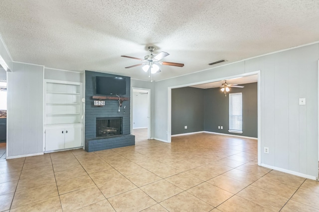 unfurnished living room featuring built in shelves, visible vents, a brick fireplace, and ceiling fan