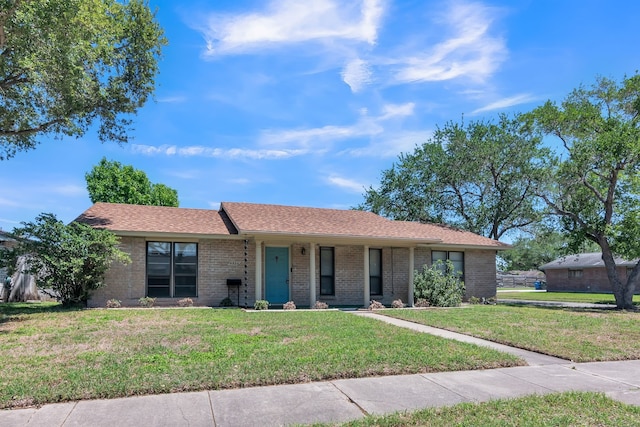 ranch-style home featuring a shingled roof, brick siding, and a front lawn