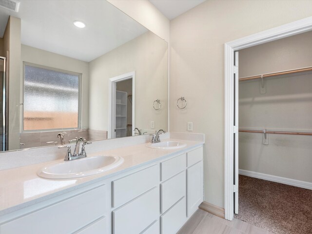 7602 Magnolia Orchid Ln, Cypress, TX 77433 - bathroom featuring a walk in closet, double vanity, visible vents, and a sink
