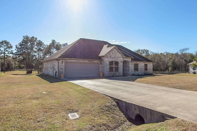 french country style house featuring concrete driveway, a front yard, brick siding, and an attached garage
