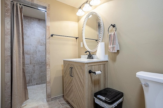 full bathroom featuring vanity, a tile shower, and toilet