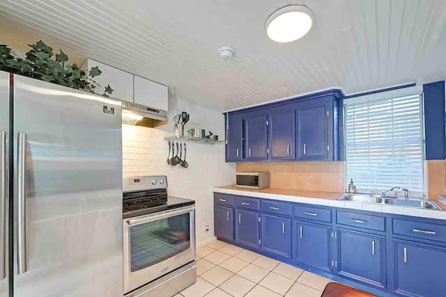 1265 Du Barry Ln, Houston, TX 77018 - kitchen featuring light tile patterned floors, a sink, blue cabinetry, and appliances with stainless steel finishes