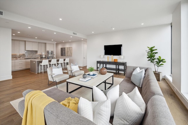 living area with visible vents, light wood finished floors, and recessed lighting