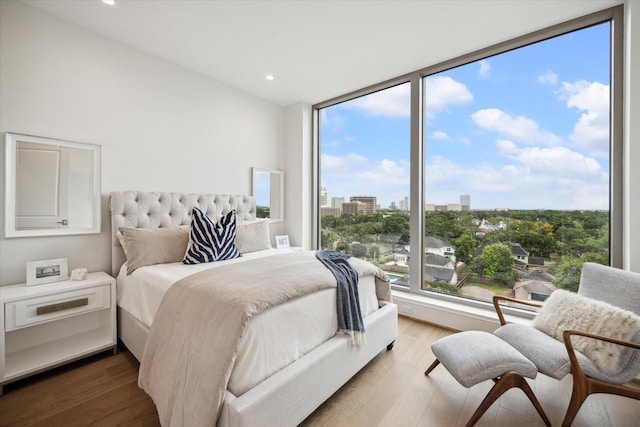 bedroom with a city view, wood finished floors, and recessed lighting