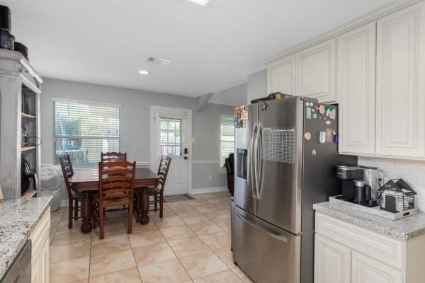 kitchen with stainless steel appliances, light tile patterned floors, baseboards, and light stone counters