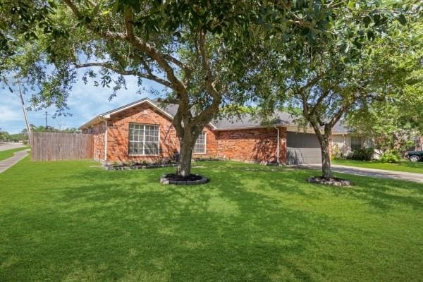 ranch-style home with an attached garage, driveway, fence, and a front lawn