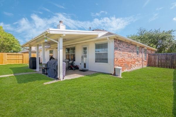 rear view of property with a patio, a fenced backyard, and a lawn