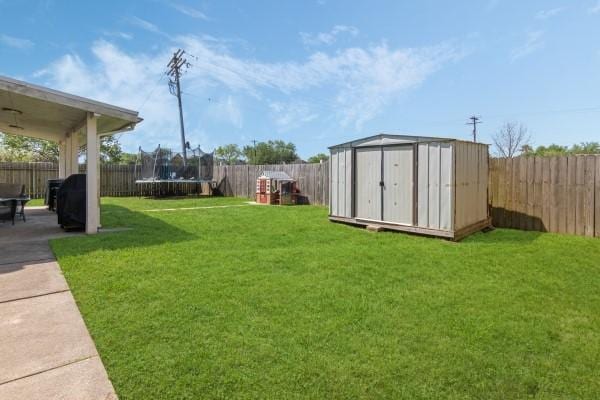 view of yard featuring a shed, a trampoline, a fenced backyard, an outdoor structure, and a patio