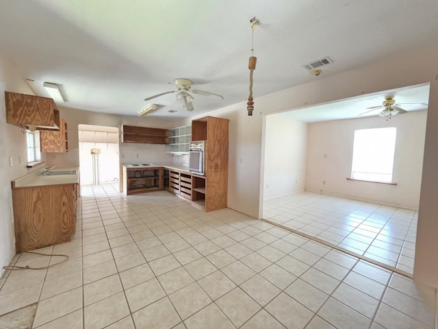 900 Mariner St, Sargent, TX 77414 - kitchen featuring light tile patterned flooring, ceiling fan, visible vents, and brown cabinetry