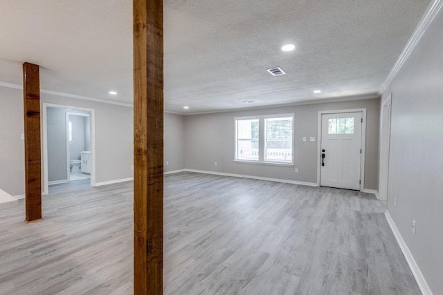 foyer entrance with baseboards, light wood-style flooring, visible vents, and ornamental molding