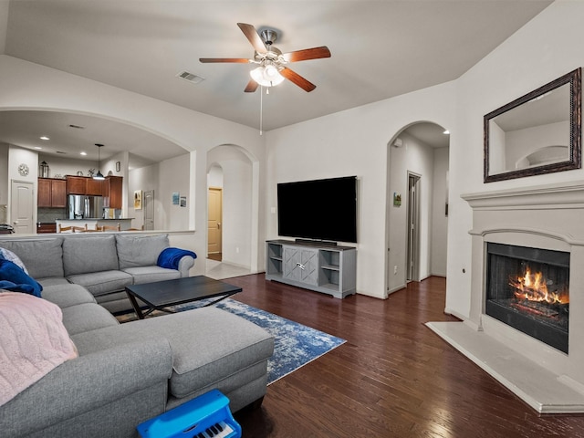 605 Pedernales St, Webster, TX 77598 - living room featuring dark wood finished floors, ceiling fan, a warm lit fireplace, arched walkways, and baseboards