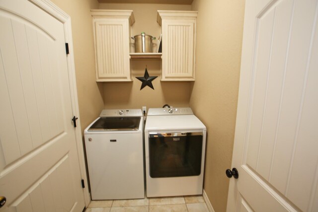 washroom featuring cabinet space, baseboards, separate washer and dryer, and light tile patterned flooring