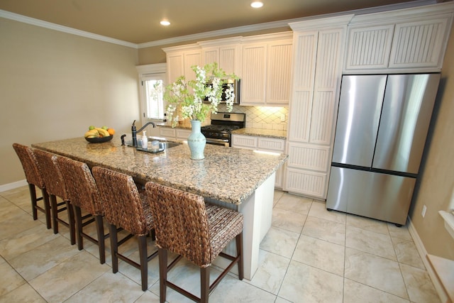 kitchen with crown molding, a kitchen breakfast bar, a kitchen island with sink, a sink, and stainless steel appliances