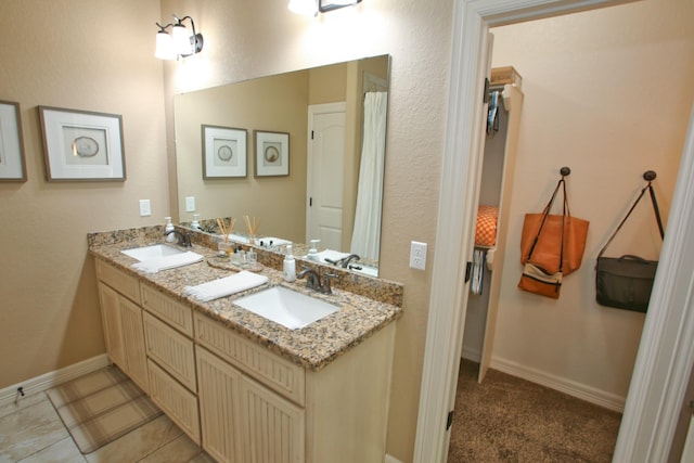 full bathroom with a sink, baseboards, and double vanity