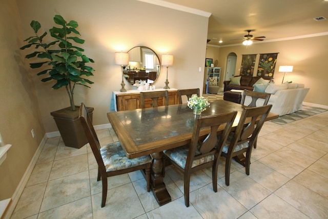 dining room with light tile patterned floors, baseboards, arched walkways, ornamental molding, and ceiling fan
