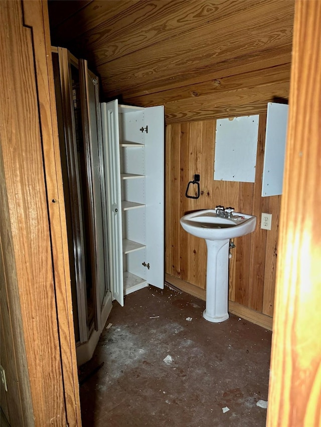 bathroom featuring wooden ceiling, wood walls, and a sink