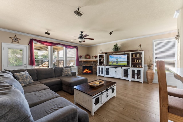 living area with ornamental molding, ceiling fan, hardwood / wood-style flooring, and a textured ceiling
