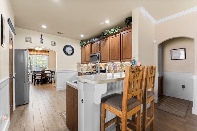 kitchen with arched walkways, a peninsula, visible vents, appliances with stainless steel finishes, and a breakfast bar area