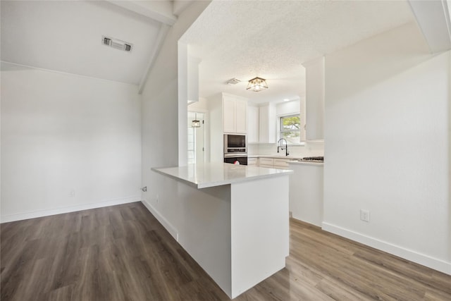 12418 A Bar Dr, Santa Fe, TX 77510 - kitchen with built in microwave, a sink, white cabinetry, a peninsula, and wood finished floors
